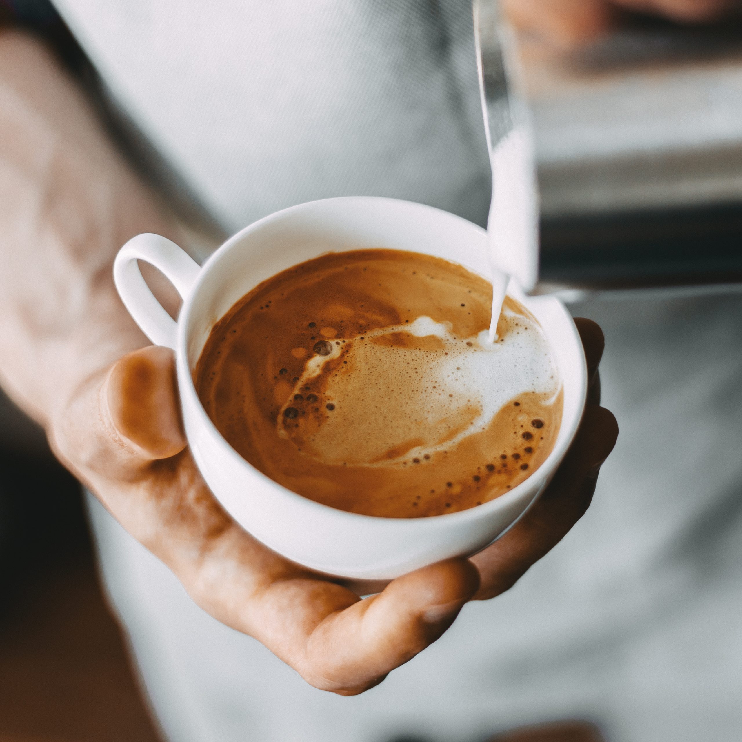 Barista making tasty appetizing coffee cappuccino latte pouring milk. Coffee preparation concept. Closeup. Horizontal. Square.